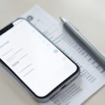 A phone showing a subscriptions settings screen next to a bank statement, representing auditing an app subscription charge