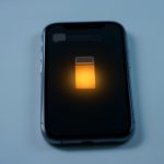 A smartphone showing a low battery indicator and a stack of delayed notification icons, illustrating battery settings delaying alerts