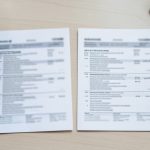 A driver comparing two car insurance declarations pages side by side at a desk before switching providers