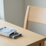 An upper-arm blood pressure monitor and cuff resting on a table beside a chair positioned for a correct seated reading