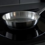 A frying pan sitting on a black glass induction cooktop, illustrating an induction cooktop that shuts off with certain pans
