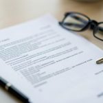A tenant reading a lease renewal addendum document at a table with a pen, reviewing the clauses before signing