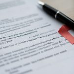 A tenant pausing with a pen over a lease renewal document, hesitating at a concerning clause before signing