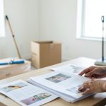 A tenant organizing a folder of cleaning invoices and move-out photos on a table in an empty apartment