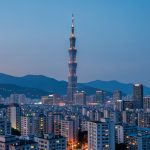 The Taipei city skyline at dusk with Taipei 101 rising above lit apartment buildings