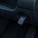 A small OBD2 scanner dongle plugged into the diagnostic port under a car dashboard