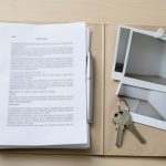 A tenant assembling documents and photos into a folder to dispute a security deposit deduction with a demand letter