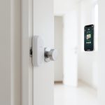 A smart lock attached to the inside of an apartment door over an existing deadbolt thumbturn