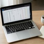 A laptop showing a budget spreadsheet with a list of subscriptions on a tidy desk, illustrating tracking paused subscriptions