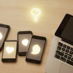 A family's several phones and a laptop on a table with a key icon, representing setting up passkeys across a household