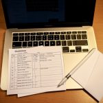 A student at a laptop with an official school transcript document and an envelope on the desk