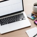 A gig worker at a desk with a laptop, a phone showing rideshare and marketplace apps, and 1099 tax forms