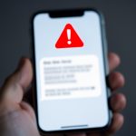 A smartphone showing a suspicious text message with a warning symbol, representing an unpaid toll smishing scam